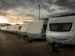 A lineup of travel trailers for sale under a dark cloudy sky.