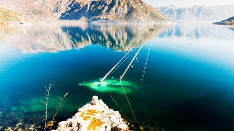 A sailboat sitting at the bottom of lake.