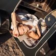 A person lays in their black travel trailer hot from the sun.