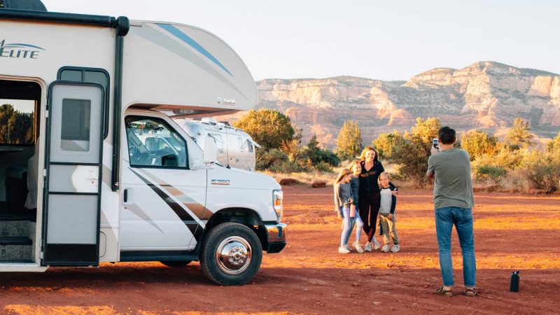 A family takes a photo outside of their Class C Motorhome