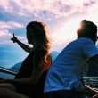 A couple silhouetted by the setting sun on a boat out in the water.