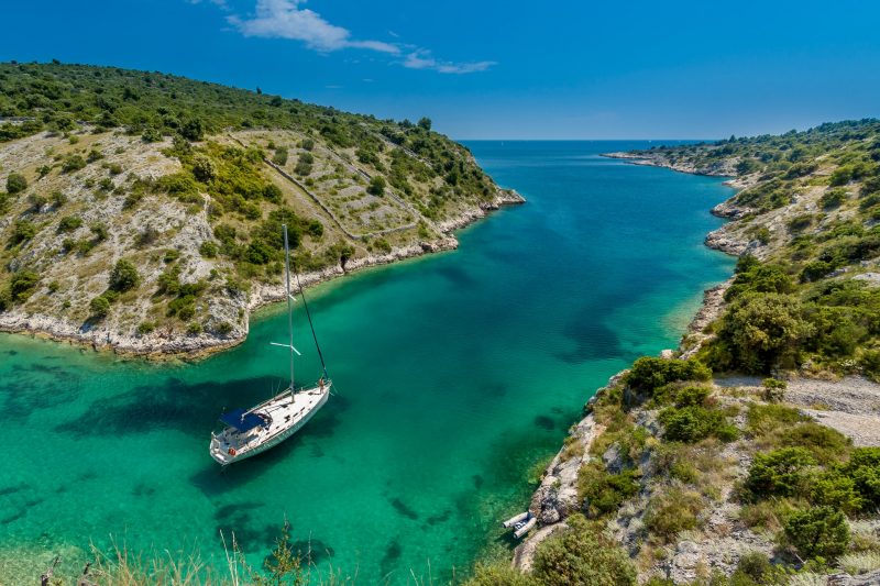 A sailboat passes through a channel towards the Ocean