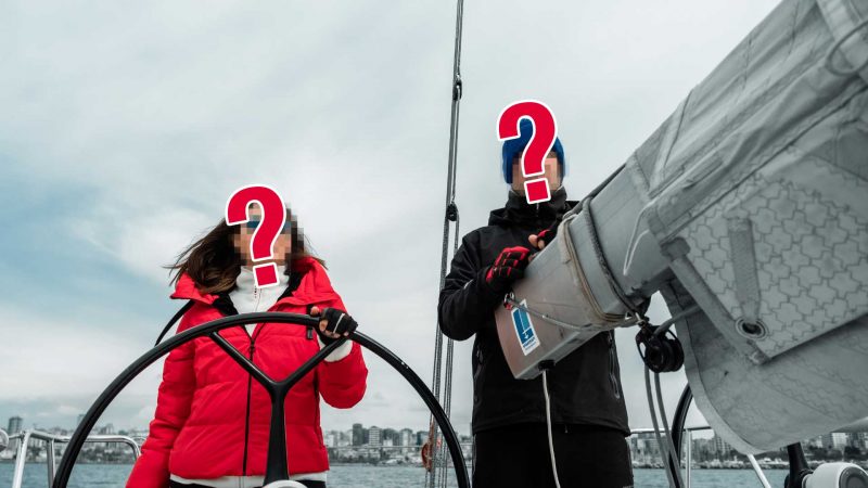 Two unidentified sailors on a sailboat at sea.