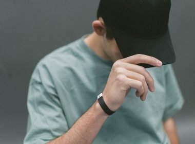 A man covers his eyes with the brim of his black ball cap.