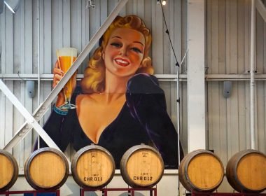 A huge signn of a woman from the 1960's drinking a beer out of a glass in a brewery