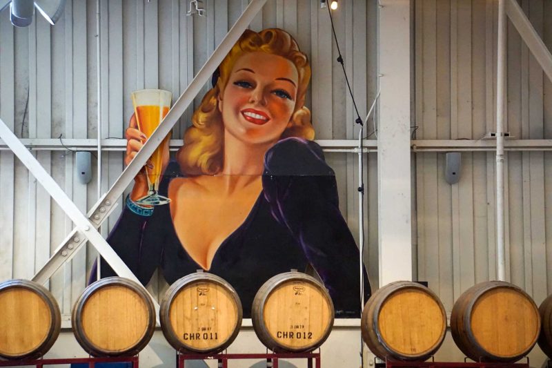 A huge signn of a woman from the 1960's drinking a beer out of a glass in a brewery