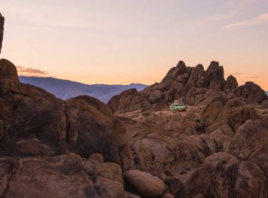 A van boondocking in the middle of rocky desert terrain at sunset.