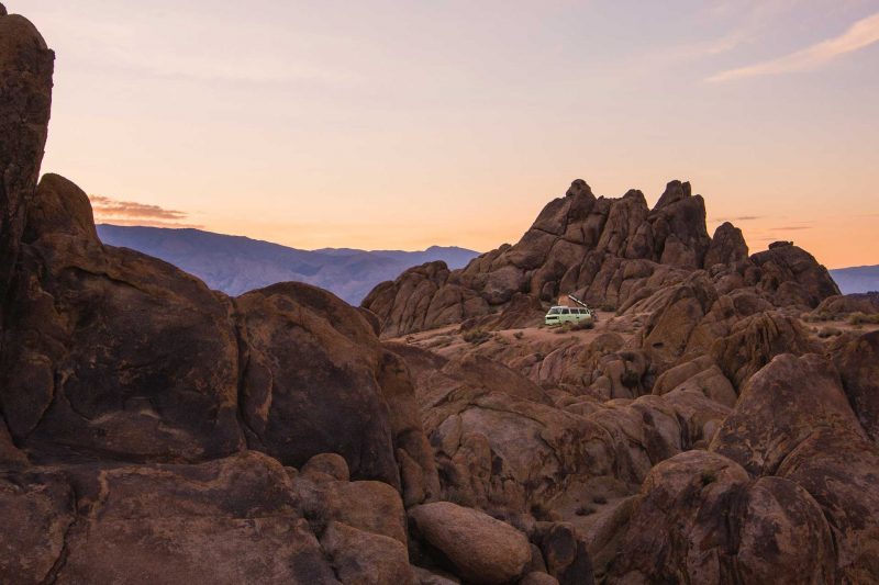 A van boondocking in the middle of rocky desert terrain at sunset.