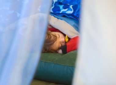 A young child sleeping on an air mattress while on a camping trip