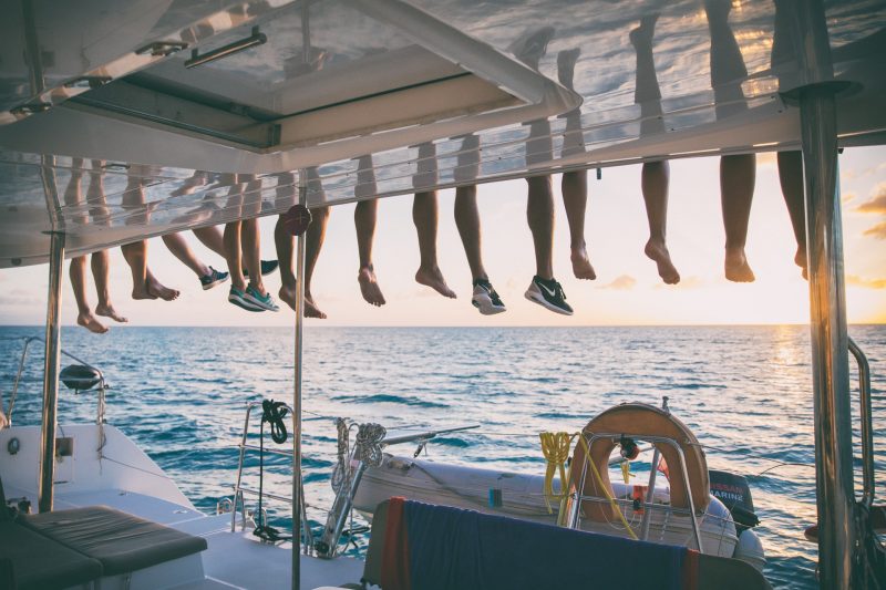 Sundown on a sailing yacht with the crew's legs dangling over the roof to enjoy the view.