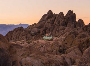 A van boondocking in the middle of rocky desert terrain at sunset.