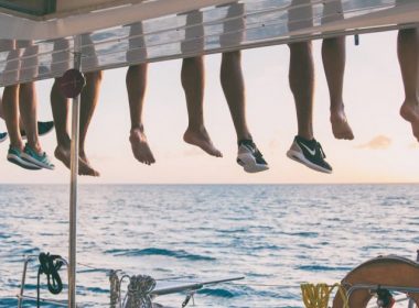 Sundown on a sailing yacht with the crew's legs dangling over the roof to enjoy the view.