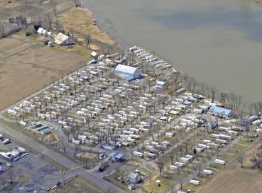 Aerial view of a packed campground next to a dirty river.