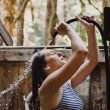 A woman spray water out of a hose under her head.
