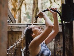 A woman spray water out of a hose under her head.
