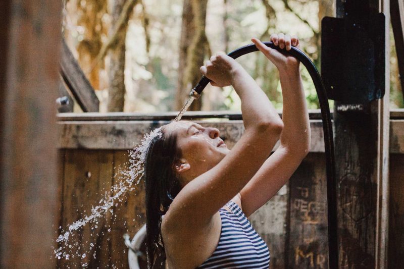 A woman spray water out of a hose under her head.