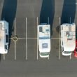 An aerial view of camper vans parked in a retail lot, taking up multiple spaces.