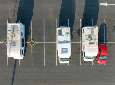 An aerial view of camper vans parked in a retail lot, taking up multiple spaces.