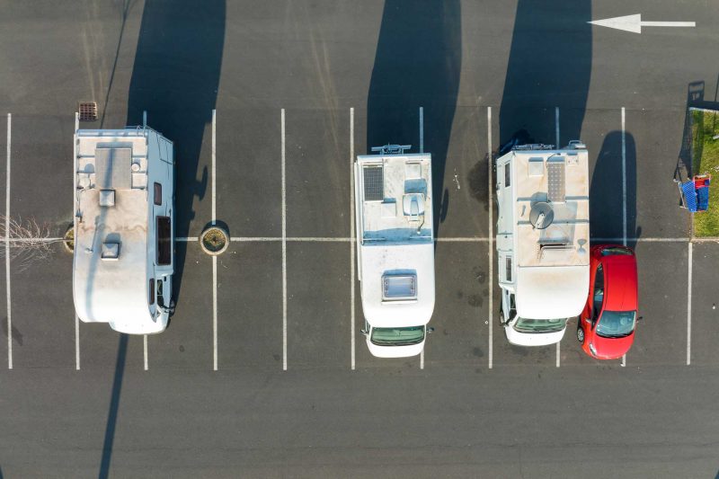 An aerial view of camper vans parked in a retail lot, taking up multiple spaces.
