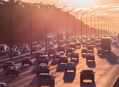Heavy traffic on a six lane highway with a hazy sunrise.