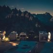 Campers with their lights on parked in a mountain campground.