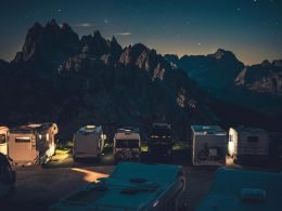 Campers with their lights on parked in a mountain campground.