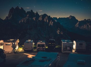 Campers with their lights on parked in a mountain campground.