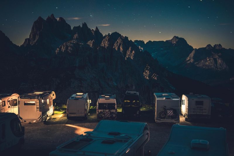 Campers with their lights on parked in a mountain campground.