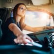 A professional female truck driver with aviator sunglasses driving a semi.