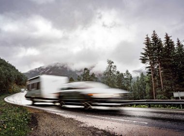 Caravan car travels on the highway at high speed on wet pavement.