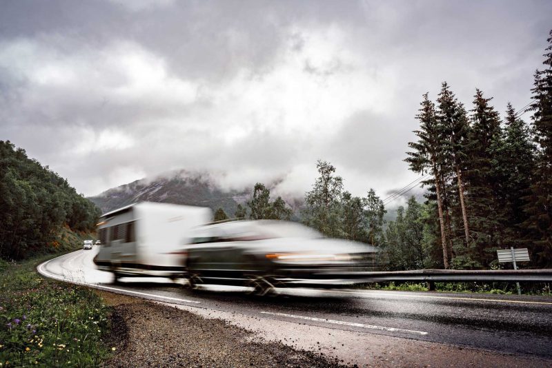 Caravan car travels on the highway at high speed on wet pavement.