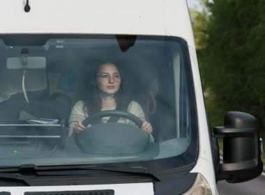 A woman driving a camper van RV down the highway looking for a place to stop.