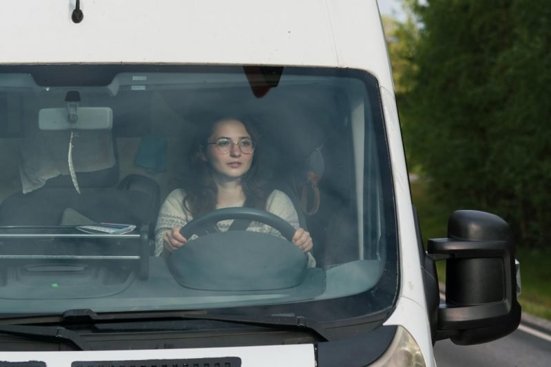 A woman driving a camper van RV down the highway looking for a place to stop.