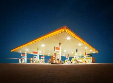 A gas station lit up at night against a starry sky.