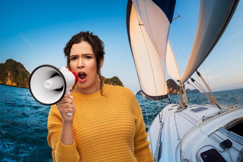 A woman shouting into a megaphone and a sailboat in the background.