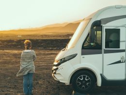 A woman wrapped in a cardigan holds herself outside of her motorhome wondering if this is the life she wanted.