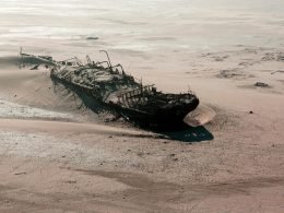 An aerial shot of a ship half buried in the dune sands along the Skeleton Coast