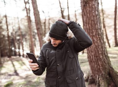 A man walks alone in the forest, checking his phone for signal as he realizes he is lost.