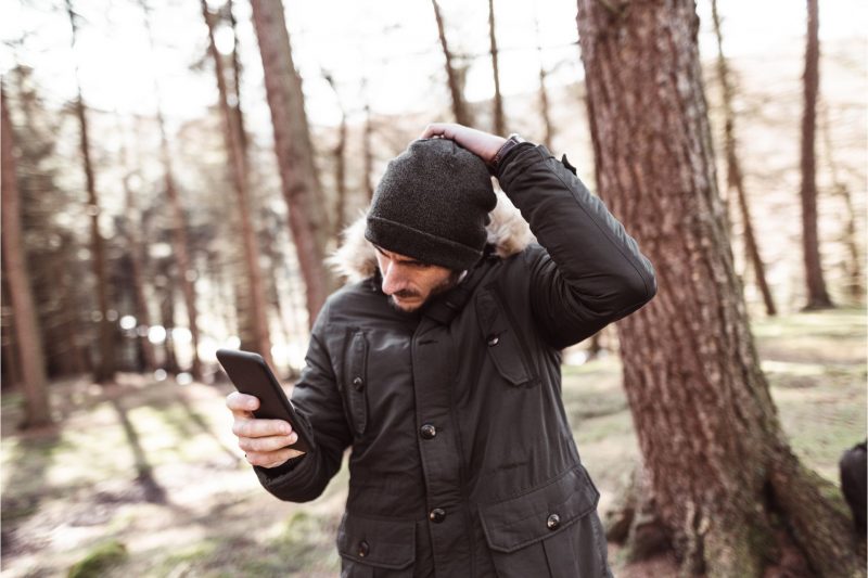 A man walks alone in the forest, checking his phone for signal as he realizes he is lost.