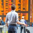 A traveler stands in front of an arrival and departure board in an ariport and sees hundreds of canceled flights.
