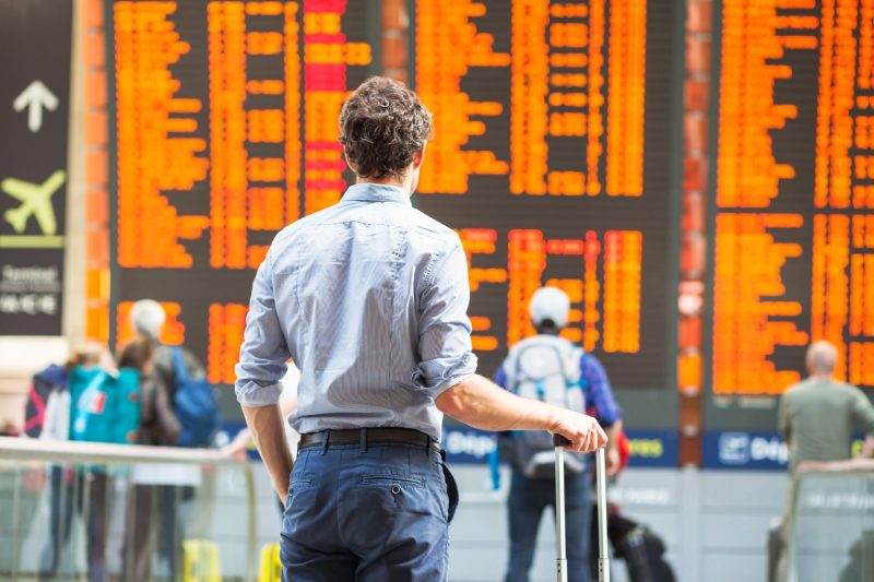 A traveler stands in front of an arrival and departure board in an ariport and sees hundreds of canceled flights.