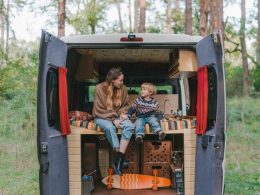 A mother a son enjoy the trees around their campsite from the back of their campervan.