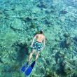 From above, a man snorkels in clear ocean water with the reef below.