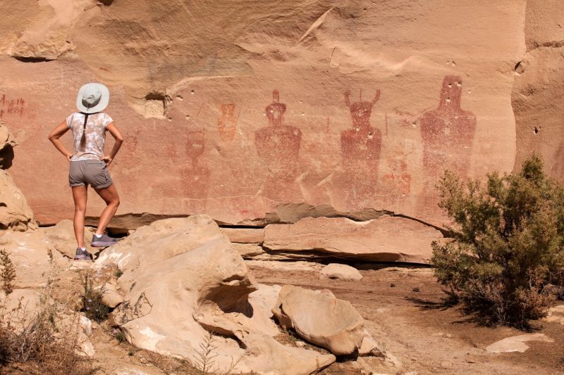 A tourist stands to admire the petroglyphs at Sego Canyon but it has been vandalized.