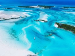From high above, turquoise blue waters shine brilliantly in the sun along the Exuma Islands in the Bahama.