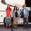 Three friends standing with their luggage in front of an RV, ready to go on a cross country trip.