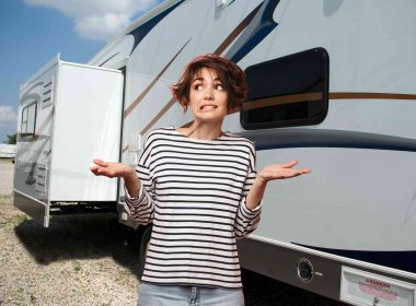 Unsure in front of the decals on an RV in a parking lot.