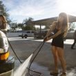 A young woman power washes her camper van.