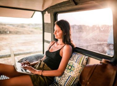 Woman in the back of a camper van using her laptop.