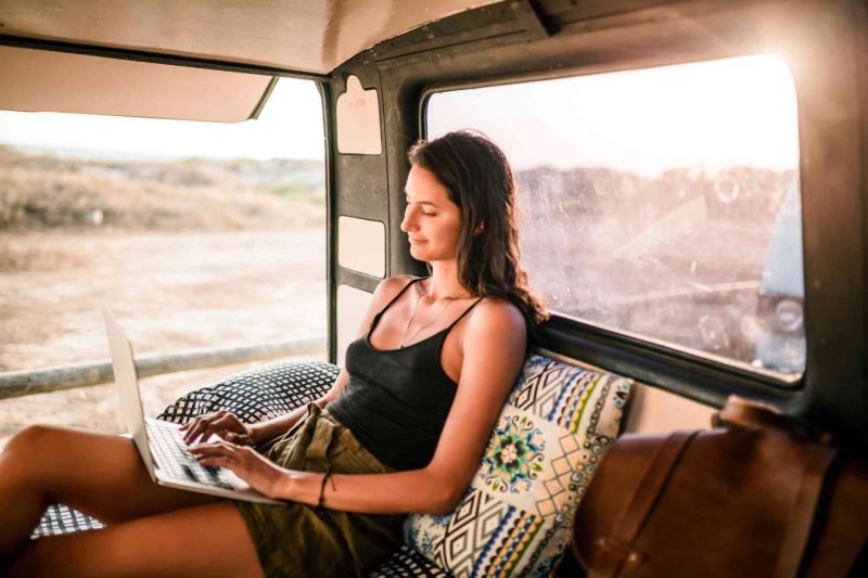 Woman in the back of a camper van using her laptop.